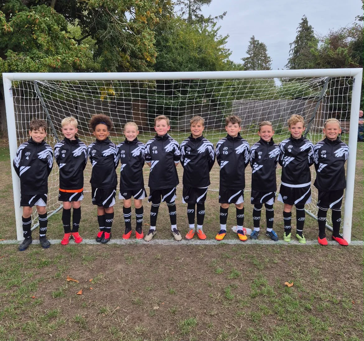 Junior football team together in matching black and white FTACT kit