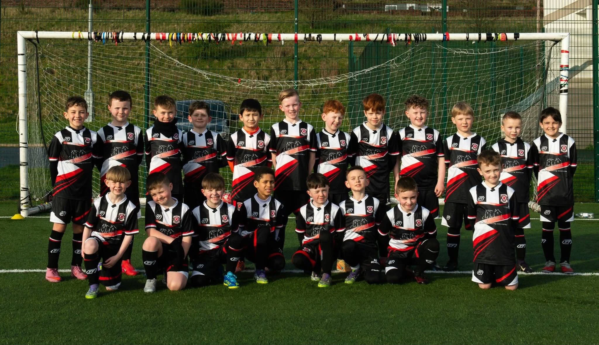 Grassroots squad in black, white and red FTACT kit together in front of a goal