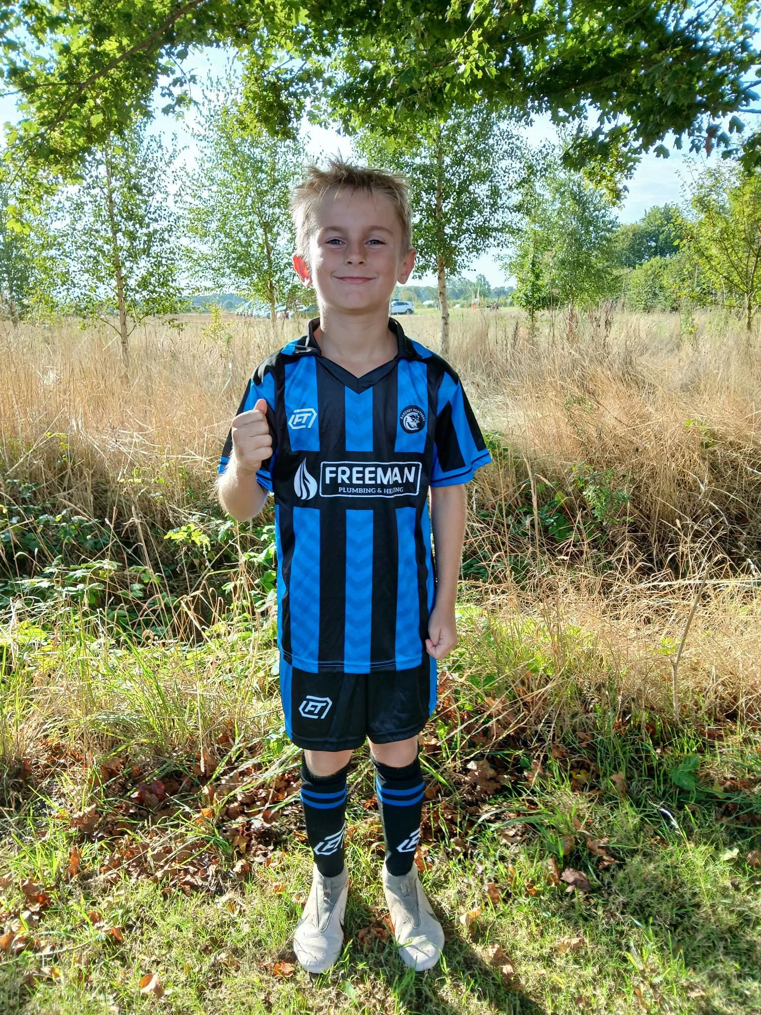 Young player smiling in their blue and black FTACT club kit