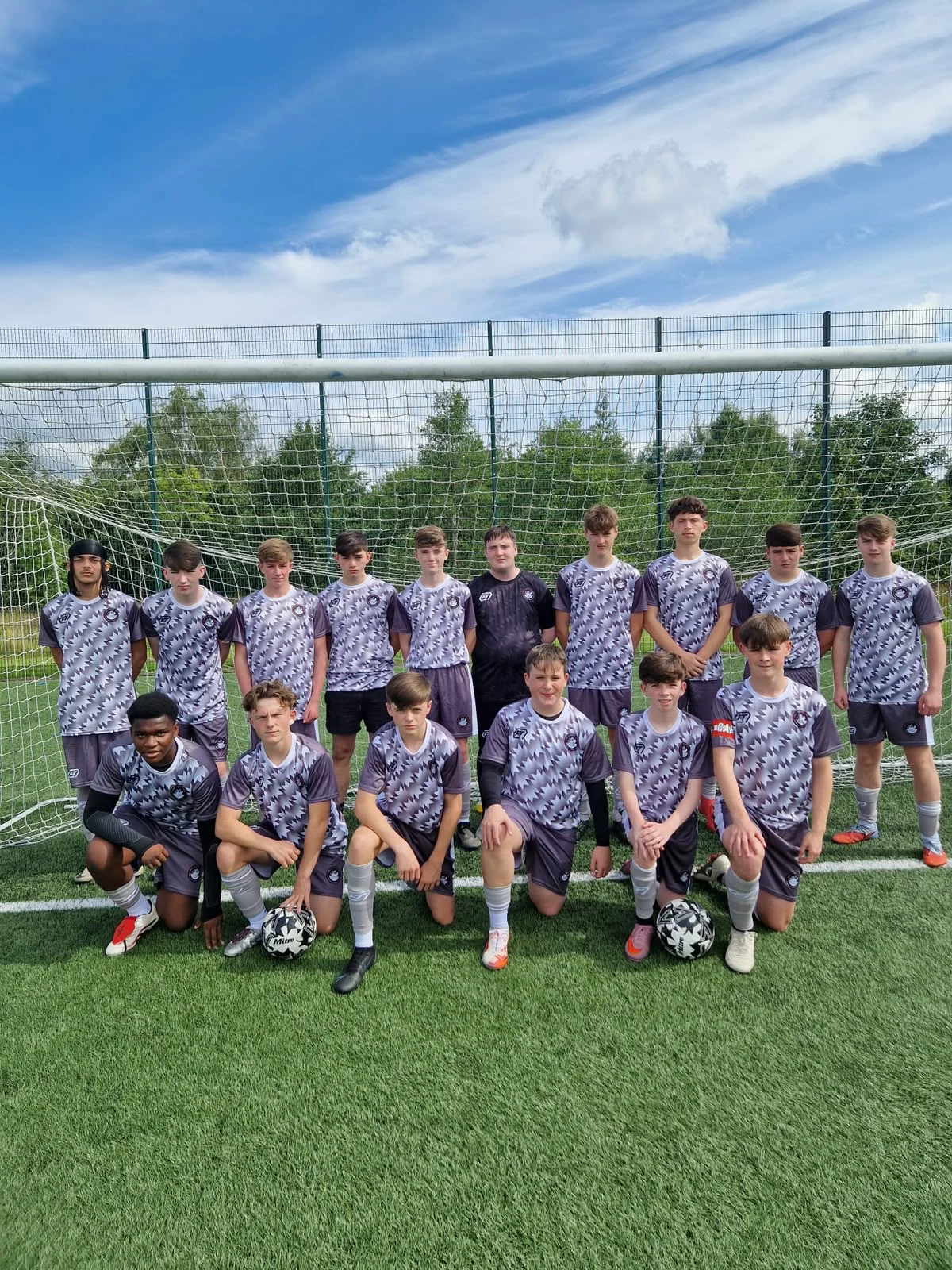 Youth football squad in grey patterned FTACT kit in front of a goal